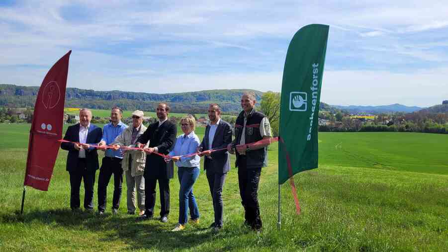 Mehrere Personen auf Wiese zwischen zwei Wimpeln