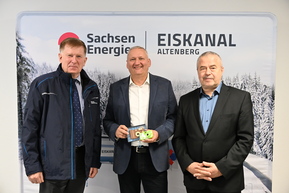 drei Personen vor Werbewand