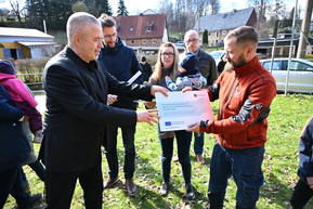 mehrere Personen auf Wiese mit Fördermittelbescheid