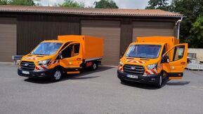 zwei Transporter in Orange vor Garagen