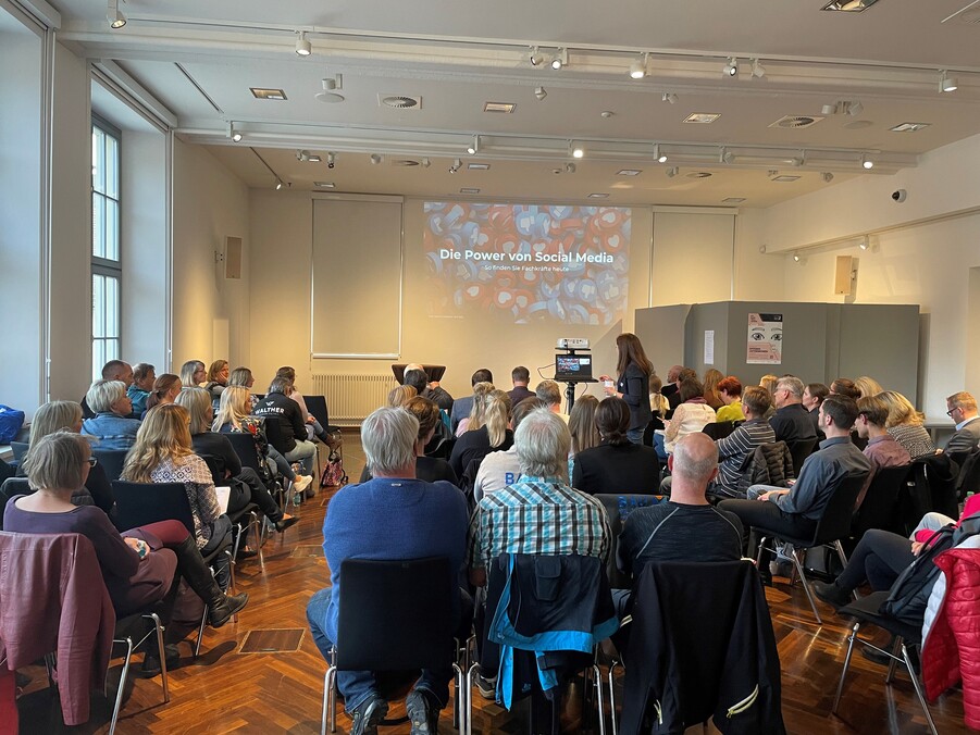 Arbeitskreis SCHULEIWRTSCHAFT in Glashütte. Mehrere Reihen Auditorium hören einer PowerPoint Präsentation zu. 