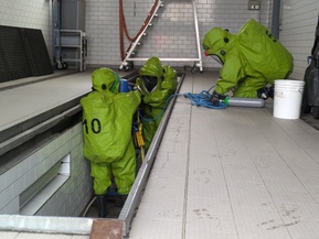 mehrere Personen in grünem Overall an einem Schieber