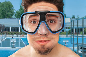 Mann mit Taucherbrille vor Schwimmbecken
