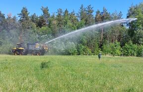 Sachsenforst Feuerlöschsystem mit Wasserstrahl vor Wald auf Wiese