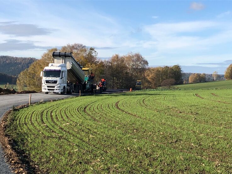 Sanierungsarbeiten mit Lastkraftwagen auf Straße neben Grünland