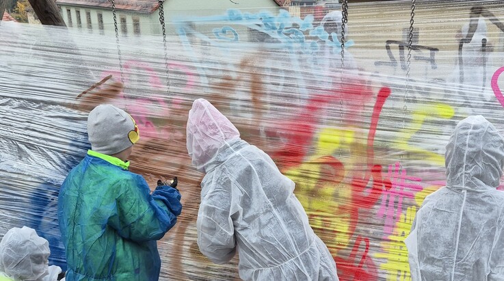 junge Menschen sprühen bunte Grafittis auf Folienwände