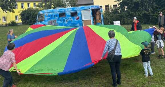 Kinder spielen mit einem Schwungtuch zum Sommerfest der Pflegeltern 2026
